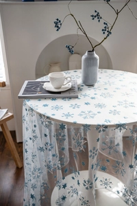 Detail of white mesh Christmas tablecloth with blue and silver embroidered snowflakes