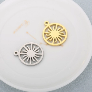 Sun gear pendants in gold and silver finish on a white ceramic plate for DIY jewelry