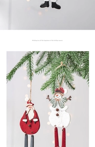 Detail of wooden painted Santa and snowman ornaments hanging on festive pine branches