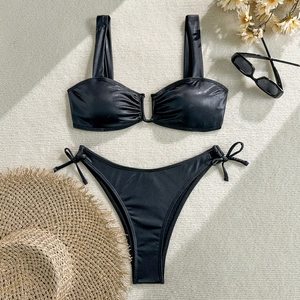 Flat lay of shiny black two-piece bikini with U-shaped hardware and side-tie bottoms