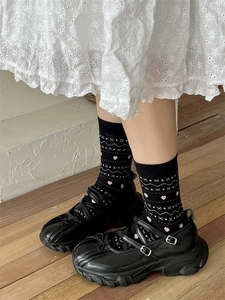 Gros plan de chaussettes noires à cœurs et chaussures Mary Jane à plateforme