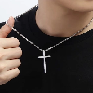 Close-up of a silver titanium steel cross pendant necklace worn over a black t-shirt