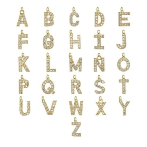 Macro shot of 26 gold alphabet pendants with pavé-set rhinestones on a white background