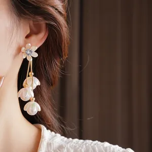 Zircon flower tassel pearl drop earrings in gold finish worn by model in high detail