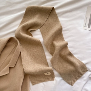 Detail of camel wool blend knitted scarf featuring a minimalist ese brand label