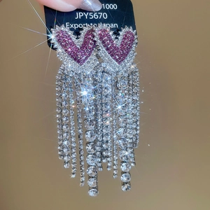 Close-up of sparkling heart fringe earrings with purple rhinestones and silver tassels