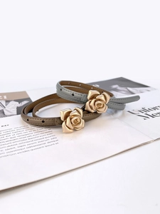 Detail of grey-blue and brown slim leather belts with 3D rose metal buckles on magazine