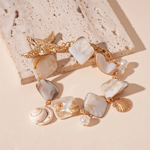 Detail of ocean-style gold chain with starfish, resin beads and pearls on stone