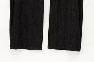Dettagli del tessuto denim scuro e cuciture dell'orlo di questi pantaloni svasati