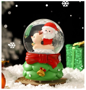 Close-up of Santa Claus on a reindeer inside a snow globe with a green tree base