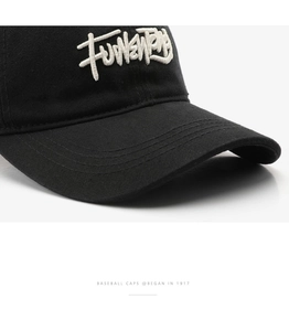 Close-up of premium 3D embroidery on a black washed cotton baseball cap texture