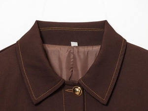 Close-up of brown lapel jacket featuring gold contrast stitching and metallic button