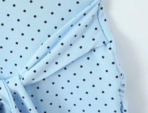 Detail of light blue polka dot romper showing ribbed texture and waist tie knot design