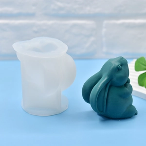White silicone praying rabbit mold with a light green resin cast on a blue tabletop