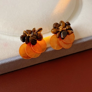 Detail of vintage earrings with tiger eye beads and orange translucent charms on a stand