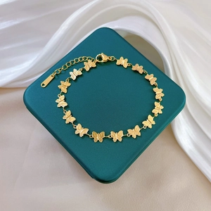 Elegant gold titanium steel butterfly link bracelet displayed on a dark green jewelry box