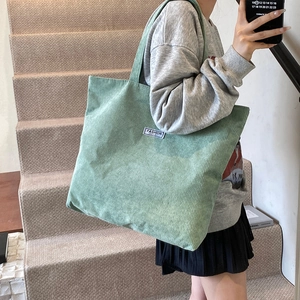 Detail shot of mint green corduroy tote bag showing textured fabric and fashion label