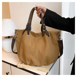 Macro view of khaki canvas tote featuring durable brown webbing handles and metal hardware