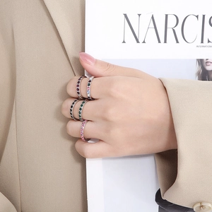 Detail of five-piece set of colorful zircon rings worn by model on neutral background