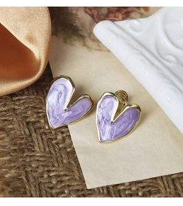 Détail de boucles d'oreilles cœur en marbre violet avec cadre doré et clip arrière