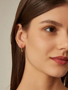Detailed view of gold beaded hoop earrings with a textured finish on a model