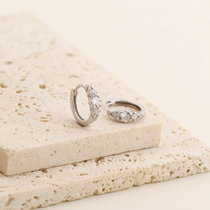 Macro shot of silver S925 hoop earrings with sparkling zircon stones on stone base