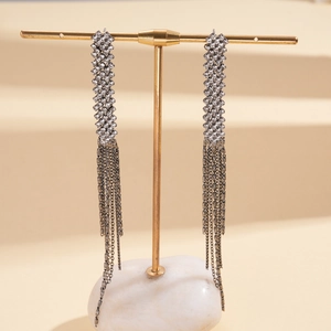 Detail of luxury rhinestone tassel earrings with hanging chains on a display stand
