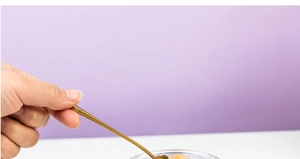 Detail showing a golden spoon scooping food from a 200ml borosilicate glass baby food jar