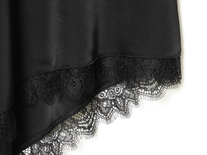 Detail of black silk satin hem with intricate eyelash lace trim and refined texture