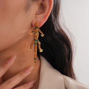 Detailed close-up of a luxury lizard earring with orange and green crystals on a model