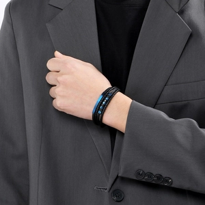 Close-up of a man in a gray suit wearing a blue and black braided leather bracelet