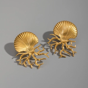Macro detail of gold-plated titanium shell and coral earrings with a polished metal finish
