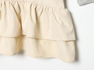 Nahaufnahme des zweilagigen Volants am cremefarbenen Minirock mit Twill-Stoffstruktur