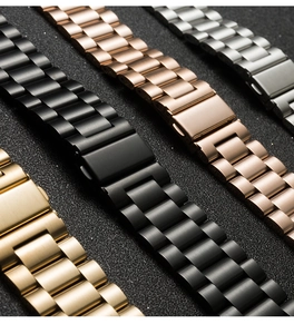 Dettaglio di cinturini in metallo nei colori oro, nero, oro rosa e argento su sfondo nero