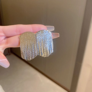 Detail of silver geometric fringe earrings held by hand showing flowing metal chains