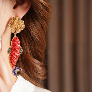 Macro view of gold flower earrings with red enamel koi fish and blue rhinestone details