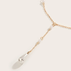 Detail of gold chain necklace featuring white pearls and a teardrop pearl pendant