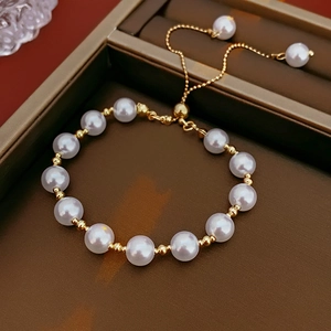 Detail of adjustable French style pearl bracelet featuring gold beads and drawstring clasp