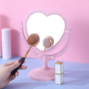 Vintage pink heart-shaped tabletop makeup mirror with ornate carving and matching base
