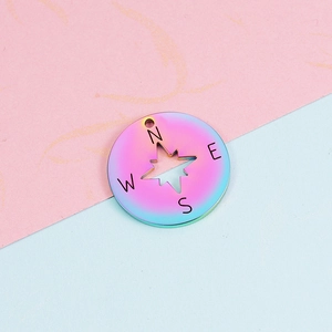 Macro shot of 22mm rainbow stainless steel compass pendant with N-E-S-W lettering