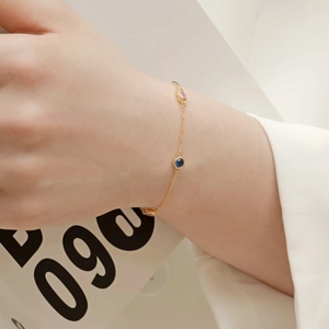 Detail of a gold-plated S925 silver bracelet with blue and pink cubic zirconia on a wrist