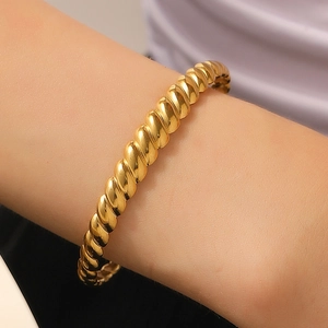 Close-up of a twisted gold rope bracelet featuring a minimalist open-ended metal design