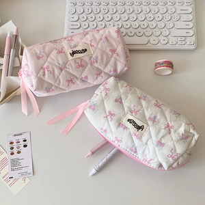 Quilted cotton pencil bags with pink bow pattern and floral design on a white desk