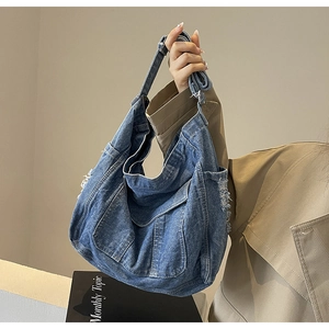 Détail du sac à bandoulière en denim bleu avec franges effilochées et texture vintage