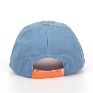 Detail of the blue kids baseball cap showing orange velcro strap and cotton texture