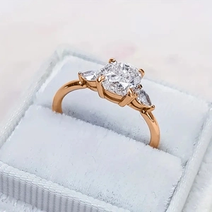 Macro detail van een roségouden drie-stenen ring met kussengeslepen edelsteen