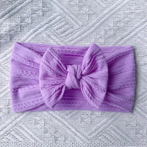 Close-up of a soft purple nylon cable knit baby headband with a large matching bow