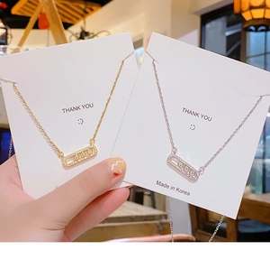 Detail of gold and silver geometric necklaces with sliding zircons on a white card