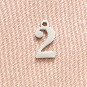 Macro shot of polished silver stainless steel number two pendant on pink fabric