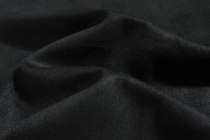 Macro shot of premium black velvet fabric texture with soft ripples and subtle silk luster